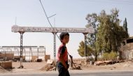 A boy walks past a sign which reads 'Islamic State in Iraq and Syria' as fighting continues between the Syrian Democratic Forces and Islamic State militants in Raqqa, Syria, August 20, 2017. REUTERS/Zohra Bensemra
