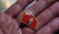 A Chinese vendor displays a pin with an image of North Korean founder Kim Il Sung, in the border city of Dandong, opposite the North Korean town of Sinuiju, in China's northeast Liaoning province on September 3, 2017. AFP / Greg Baker