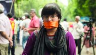 A woman covers her mouth with an orange scarf during a rally called 