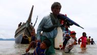 A Rohingya refugee man pulls a child as they walk to the shore after crossing the Bangladesh-Myanmar border by boat through the Bay of Bengal in Shah Porir Dwip, Bangladesh, September 10, 2017. Reuters/Danish Siddiqui