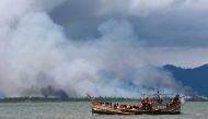 Smoke is seen on Myanmar's side of border as a boat carrying Rohingya refugees arrives on shore after crossing the Bangladesh-Myanmar border through the Bay of Bengal, in Shah Porir Dwip, Bangladesh September 11, 2017. Reuters/Danish Siddiqui