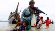  A Rohingya refugee pulls a child as they walk to shore after crossing the Bangladesh-Myanmar border by boat on Sunday. Photograph: Danish Siddiqui/Reuters.