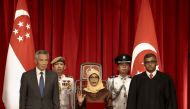 President-elect Halimah Yacob (C) takes the oath of office while flanked by Singapore Prime Minister Lee Hsien Loong (L) and Chief Justice Sundaresh Menon (R) during the presidential inauguration ceremony at the Istana Presidential Palace in Singapore Sep