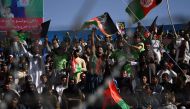 In this photograph taken on September 18, 2017, Afghan cricket fans cheer and wave the national flag during a match between Kabul Eagles and Band-e-Amir Dragons during the Shpageeza Cricket League T20 tournament at the Kabul International Cricket ground i