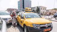 Schoolgirls get into a yellow Benin Taxi in Cotonou on September 18, 2017. AFP / YANICK FOLLY
