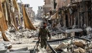 A member of the Syrian Democratic Forces (SDF) walks through the debris in the old city centre on the eastern frontline of Raqa on September 25, 2017.   AFP / BULENT KILIC
