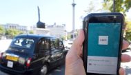 FILE PHOTO: A photo illustration a London taxi passing as the Uber app logo is displayed on a mobile telephone, as it is held up for a posed photograph in central London September 22, 2017. REUTERS/Toby Melville/File Photo
