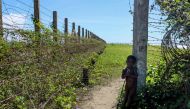 This photo taken on October 10, 2017 shows a child stand next to a barbed wire fence along the Myanmar-Bangladesh border near the Du Thar Ya village in Maungdaw, Northern Rakhine State. AFP / Marion Thibaut