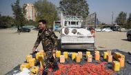 An Afghan security force personnel walks next to containers filled with explosive material after presenting to the media at the National Directorate of Security (NDS) headquarters in Kabul on October 15, 2017.  AFP / WAKIL KOHSAR

