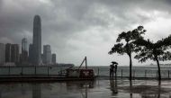 A couple uses an umbrella to shield themselves from the rain in Hong Kong on October 15, 2017 as Typhoon Khanun moves across the northern part of the South China sea. / AFP / DALE DE LA REY