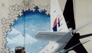 (FILES) This file photo taken on March 8, 2016 shows a Malaysian man walking in front of a mural of missing Malaysia Airlines MH370 plane in a back-alley in Shah Alam.  AFP / MANAN VATSYAYANA
