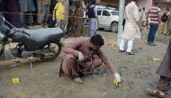 A Pakistani investigator inspects the scene of the attack on opposition politician Khawaja Izharul Hassan in Karachi in September