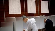 Voters fill in their ballot papers at a polling station to vote in Japan's general election in Tokyo on october 22, 2017.  AFP / Behrouz MEHRI
