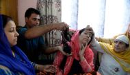 In this photograph taken on October 13, 2017, Kashmiri resident Tasleema (C), and the victim of a 'braid chopping', reacts as a man displays her hair, which was chopped off in an attack, in the Batamaloo area of Srinagar. AFP / Tauseef Mustafa