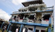 People walk in front of a bullet-riddled apartment house in a residential area in Malutlut district, Marawi city, southern Philippines October 27, 2017, which was believed to have been rented by pro-Islamic State militant group leaders Isnilon Hapilon and