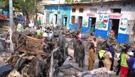 Residents walk at the scene of a blast on October 29, 2017, a day after two car bombs exploded in Mogadishu. AFP / Mohamed ABDIWAHAB
