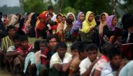 Rohingya refugees sit in a line as they wait to receive permission from the Bangladeshi army to continue their way after crossing the Bangladesh-Myanmar border, at a port in Teknaf, Bangladesh, October 31, 2017. REUTERS/Hannah McKay.