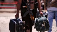 FILE PHOTO: A rebel fighter carries suitcases and his weapon prior to boarding a bus as rebel fighters the besieged Waer district in the central Syrian city of Homs Syria May 21 2017 REUTERS Omar Sanadiki