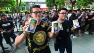 The first customers to purchase their new iPhone X smartphone pose outside an Apple store during its launch in Singapore on November 3, 2017. AFP / Roslan Rahman