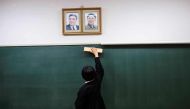 A file photo of a student cleaning the blackboard under portraits of late North Korean leaders Kim Il Sung and Kim Jong Il after an exam at Tokyo Korean high school in Tokyo October 13, 2017. / AFP / Behrouz MEHRI AND Behrouz MEHRI /