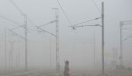 A Indian Sikh 'Nihang', or traditional Sikh army member, crosses railway tracks amidst dense smog near Amritsar railway station on November 7, 2017. / AFP / NARINDER NANU