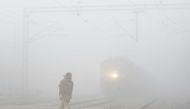 An Indian resident walks over the tracks at a railway crossing amid heavy smog in Amritsar on November 9, 2017. AFP / NARINDER NANU
