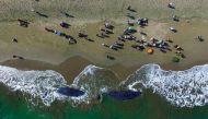 This aerial picture shows villagers looking at two dead sperm whales on a beach in Aceh Besar on November 14, 2017.  AFP / Chaideer MAHYUDDIN
