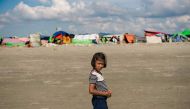 In this photograph taken on November 12, 2017, a girl stands on the sandy banks of the natural boundary between Myanmar and Bangladesh near a makeshift camp in Rakhine state in Myanmar.  AFP / Phyo Hein KYAW