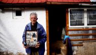 A file photo of Mile Mladic, a cousin of the former Bosnian Serb military commander Ratko Mladic, poses for a photograph holding old family photos of Ratko Mladic and his family in front of his home, in the village where Ratko Mladic was born, Bozanovici,