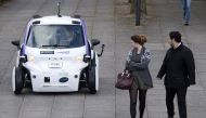 (FILES) This file photo taken on October 11, 2016 shows people looking at an autonomous self-driving vehicle, as it is tested in a pedestrianised zone, during a media event in Milton Keynes, north of London, on October 11, 2016. A driverless, electric car
