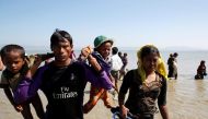 A Rohingya refugee man holding children walks towards the shore as they arrive on a makeshift boat after crossing the Bangladesh-Myanmar border, at Shah Porir Dwip near Cox's Bazar, Bangladesh, November 9, 2017. REUTERS/Navesh Chitrakar