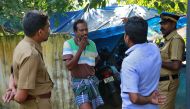 K M Ashokan (2-L), father of 24-year-old Akhila, who converted to Islam in 2016 and took a new name, Hadiya, smokes while speaking with a friend, as police officers stand guard outside his house at Vaikom in the Kottayam district of the southern state of 