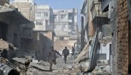 Syrian men run through an alley in the rebel-controlled town of Mesraba, in the eastern Ghouta region on the outskirts of the capital Damascus, on November 27, 2017, following reported bombardment by government forces.  AFP / ABDULMONAM EASSA