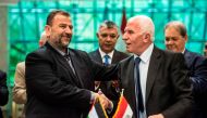 A file photo of Fatah's Azzam al-Ahmad (R) and Saleh al-Aruri (L) of Hamas shaking hands after signing a reconciliation deal in Cairo October 12, 2017. / AFP / KHALED DESOUKI