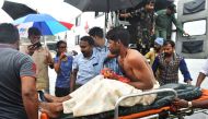 Indian officials carry a stranded fisherman, rescued by naval and air force helicopters from the Ockhi cyclone, at Thiruvananthpuram airport on December 1, 2017. / AFP / Rakesh Nair