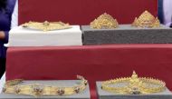 A set of returned Angkorian-era gold jewellery is displayed to the public behind protective glass during a ceremony in front of the National Museum upon its arrival in Phnom Penh on December 2, 2017. /AFP /TANG CHHIN SOTHY