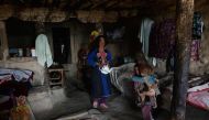 In this photograph taken on October 21, 2017 Afghan widow Janat Bibi, 65, holds a teapot walks inside her mud house in the remote village of Shemol in the eastern province of Nangarhar. AFP / NOORULLAH SHIRZADA 
