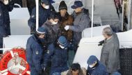 Japanese policemen escort the crew of a North Korean boat at a port in Hakodate, Japan December 9, 2017. Kyodo/via REUTERS