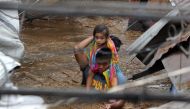 A policeman carries a young girl as he wades through a flooded street in Cagayan City on December 22, 2017, after the Cagayan River swelled caused by heavy rains brought by Tropical Storm Tembin. AFP / Josep DEVEZA