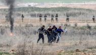 Palestinian protesters carry their wounded friend during a demonstration against US President Donald Trump's recognition of Jerusalem as Israel's capital, at Israeli border in Shuja'iyya neighborhood of Gaza City, December 22, 2017. ( Ali Jadallah - Anado