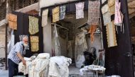 A picture taken on July 22, 2017, shows 62-year-old Mohammad Shawash sitting outside his textile shop amid the destruction in the old city of Aleppo. AFP / George OURFALIAN