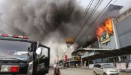 This photo taken on December 23, 2017 shows a firefighter standing in front of a burning shopping mall in Davao City on the southern Philippine island of Mindanao. / AFP.