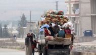 A displaced family from a village in southern Idlib repair their vehicle as they head on the Damascus-Aleppo motorway towards the northern part of the rebel-held province on December 29, 2017. / AFP / OMAR HAJ KADOUR