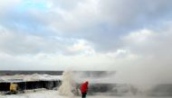 A photographer checks his equipment as waves crash over the tidal wall along the seafront in New Brighton, north west England, on January 3, 2018, as Storm Eleanor swept over the country. Storm Eleanor swept across the country overnight, bringing winds of