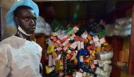 A Health Ministry employee taking part in an operation to empty shops selling fake medicine during a raid monitored by police officers against shops selling counterfeit drugs at the Adjame market in Abidjan on May 03, 2017. AFP / Issouf Sanogo