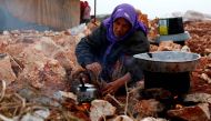 A Syrian woman, who fled from the outskirts of southern Idlib due to the conflict between government forces and opposition fighters, cooks over a fire at the make-shift camp of Kalbeed near the Bab al-Hawa crossing on the Syria-Turkey border on January 17