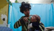 A Syrian boy holds an oxygen mask over the face of an infant at a make-shift hospital following a reported gas attack on the rebel-held besieged town of Douma in the eastern Ghouta region on the outskirts of the capital Damascus on January 22, 2018.  AFP 