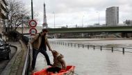 People use a dinghy to access a houseboat after the River Seine burst its banks in Paris on January 24, 2018. / AFP / Ludovic MARIN