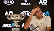 Switzerland's Roger Federer sits next to the Norman Brookes Challenge Cup during a press conferecen after beating Croatia's Marin Cilic in their men's singles final match on day 14 of the Australian Open tennis tournament in Melbourne on early January 29,