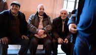 People sit outside the Court of Appeal in Paris on January 31, 2018 after former workers won in a discrimination claim made by more than 800 railway workers (Chibanis) of Moroccan nationality or origin against France's national railway company SNCF.  AFP 